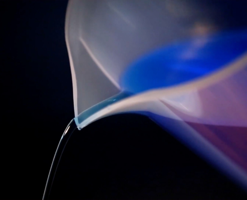 Close up of measuring cup pouring blue liquid