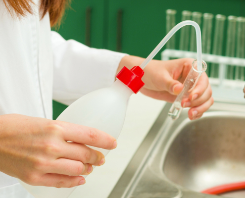 Close Up of Person Rinsing Out Beaker with Water