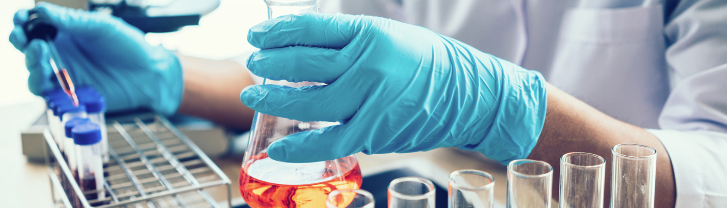 Close-up of gloved hands mixing chemicals in a beaker