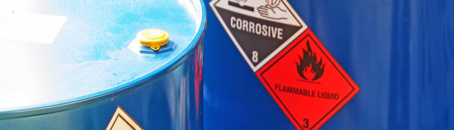 the close-up shot of blue color hazardous dangerous chemical barrels ,have warning labels of corrosive & flammable liquid in daylight on daytime